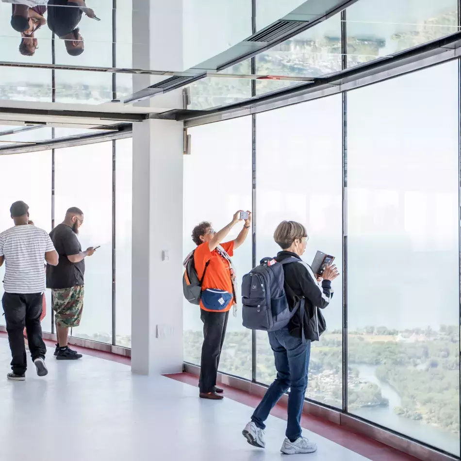 Two people looking out the window, holding cell phones to take photos.