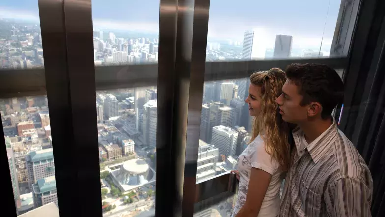 Couple in an elevator at the CN Tower looking at the view